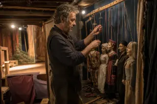 backstage marionnettist adjusting handmade puppets under warm lights in a rustic community theater