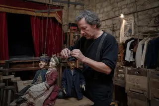 Marionettist backstage adjusting wooden puppets in a rustic community theater, with soft lighting and handcrafted props, evoking an intimate and artisanal atmosphere.