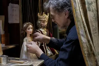 Marionettist backstage adjusting handmade puppets, warm backstage lighting, artisanal tools visible, sense of anticipation before a local children's show.